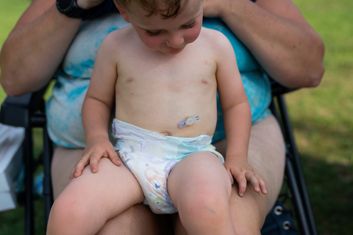 Monmouth, ME, United States -- Jay Patrick "J.P." sits on his mother, Lisa Hasch's lap at the Cochnewagon Lake, where Hasch works as a lifeguard, in Monmouth, ME on Wednesday, August 8, 2018. Lisa Hasch adopted J.P. and his older brother Devon, and J.P. was an NAS baby who arrived at 4 weeks with withdrawal symptoms that included tremors, rashes, vomiting and constant screaming. J.P. got a feeding tube in July 2017 which improved his quality of life. (Photo by Yoon S. Byun)