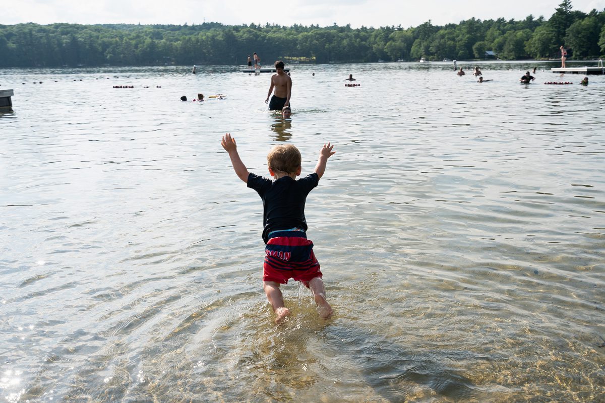 Monmouth, ME, United States -- Jay Patrick "J.P." jumps into Cochnewagon Lake, where Hasch works as a lifeguard, in Monmouth, ME on Wednesday, August 8, 2018. Lisa Hasch adopted J.P. and his older brother Devon, and J.P. was an NAS baby who arrived at 4 weeks with withdrawal symptoms that included tremors, rashes, vomiting and constant screaming. J.P. got a feeding tub in July 2017 which improved his quality of life. (Photo by Yoon S. Byun)