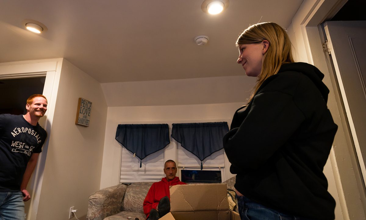 Courtney Allen speaks to residents in "JP 2," one of two James' Place residences in Augusta, ME on Thursday, November 15, 2018. At left is Ryan Gary who has been in the apartment since early October. Tim Bellavance sits on the couch in the background. (Photo by Yoon S. Byun)