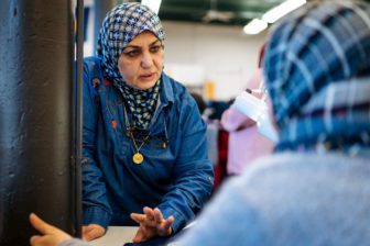 Anaan Jabbir of Portland, originally from Iraq, helps a co-worker with a stitching pattern at American Roots. Photo by Gabe Souza