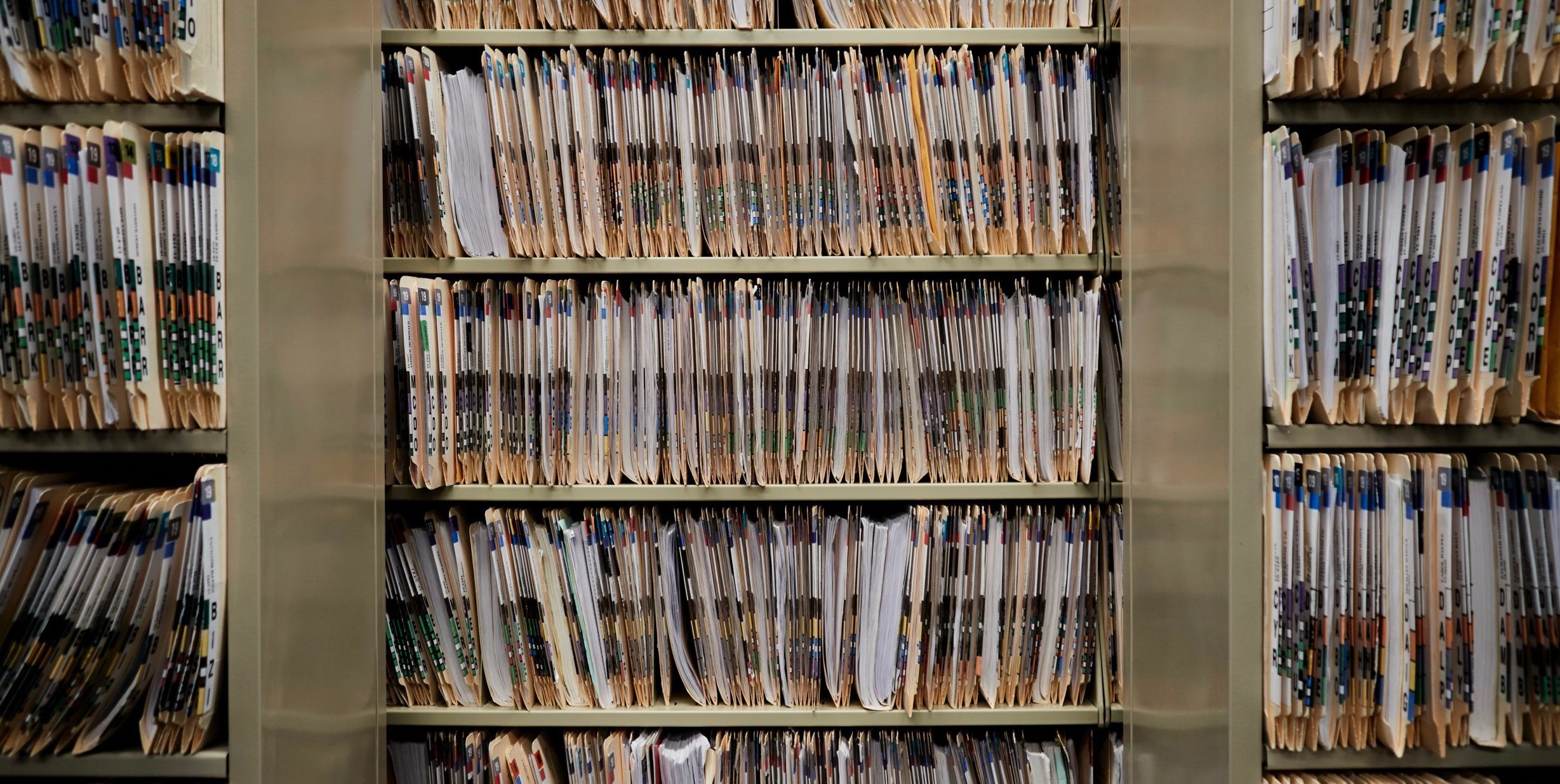 Thousands of paper court records line multiple shelves in an office.