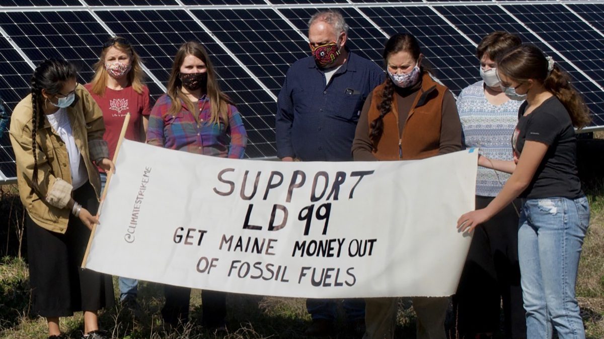 environmental activists stand with sign to divest in fossil fuels