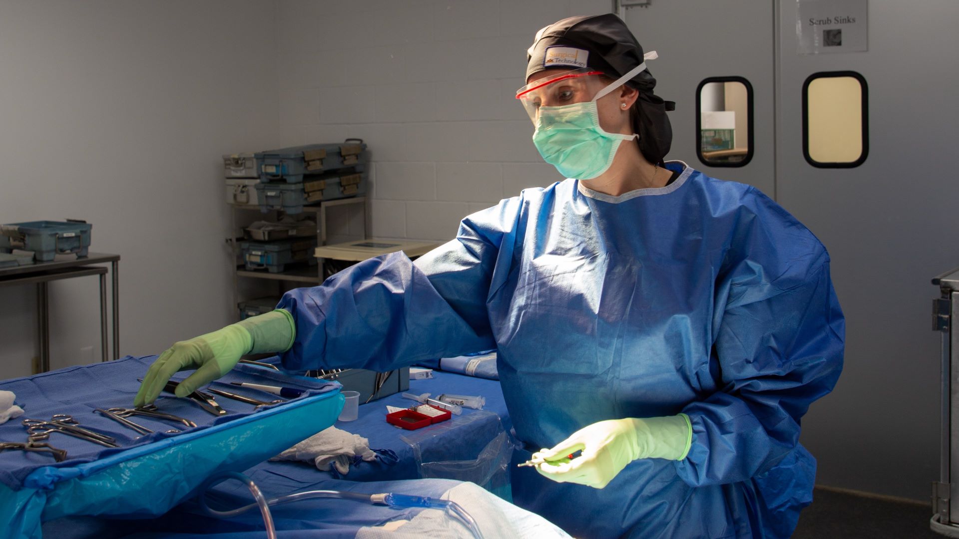 Tisha Clark, wearing surgical scrubs, demonstrates a surgical procedure at Eastern Maine Community College.