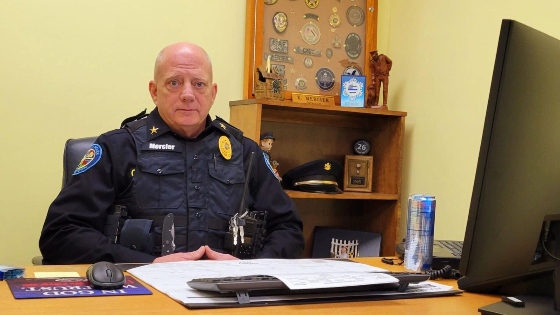 The Machias police chief poses for a photo while sitting at his desk
