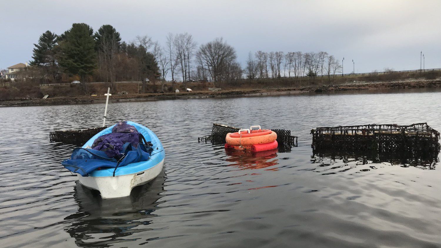 A small boat and shellfish harvesting equipment float in the water. 